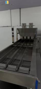 Automatic stainless steel deep fryer for donuts and cream puffs.